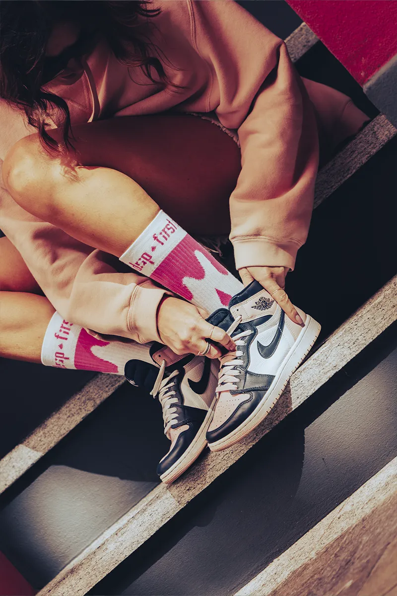 Ragazza allaccia Jordan 1 con calzini Drip rosa
