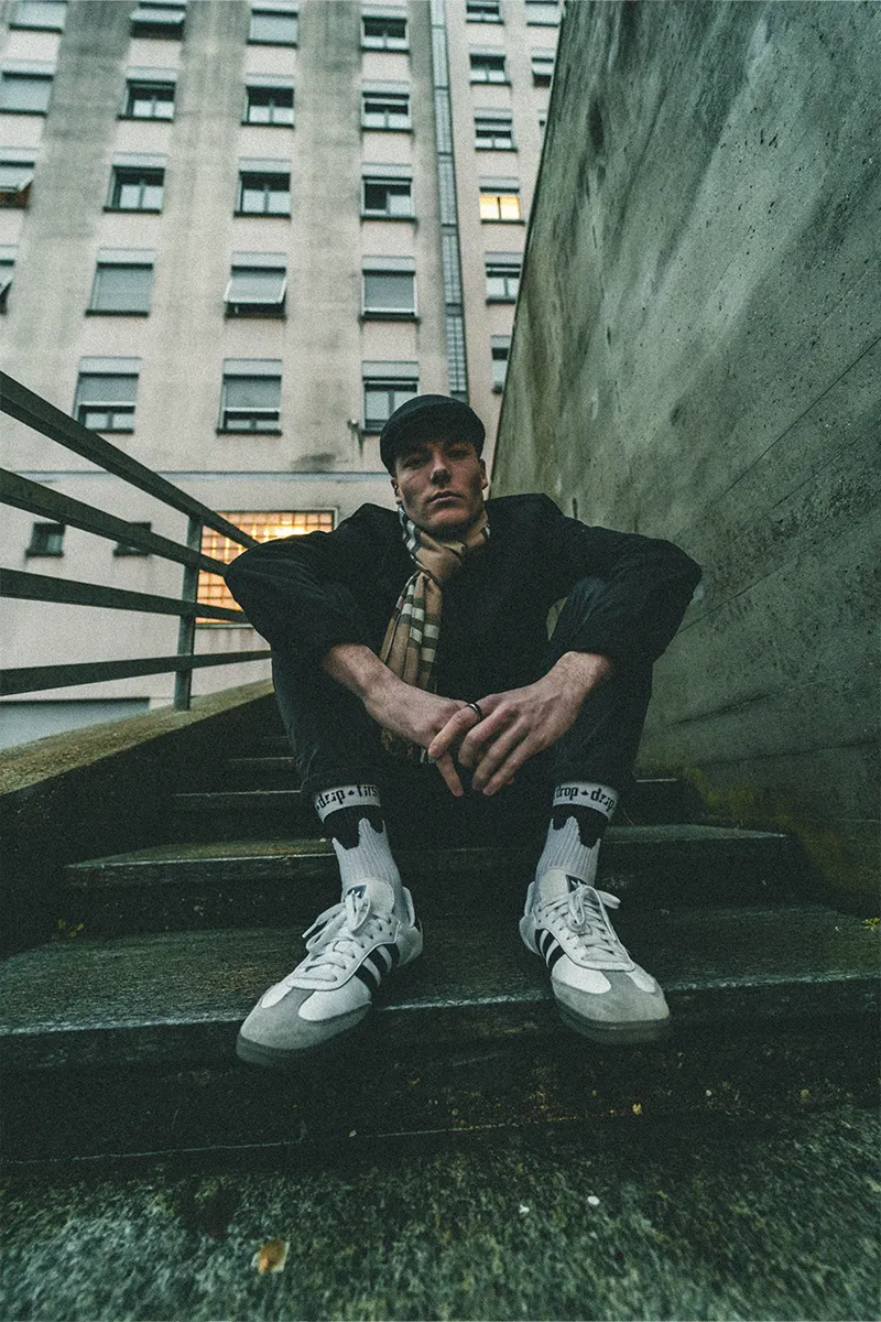 Ragazzo seduto sulle scale con calzini Drip e Adidas Samba