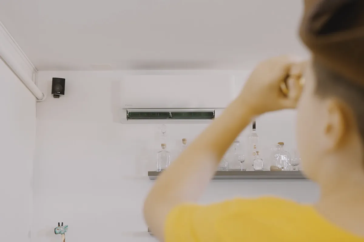 Ragazzo maglietta gialla punta telecomando climatizzatore AirWash