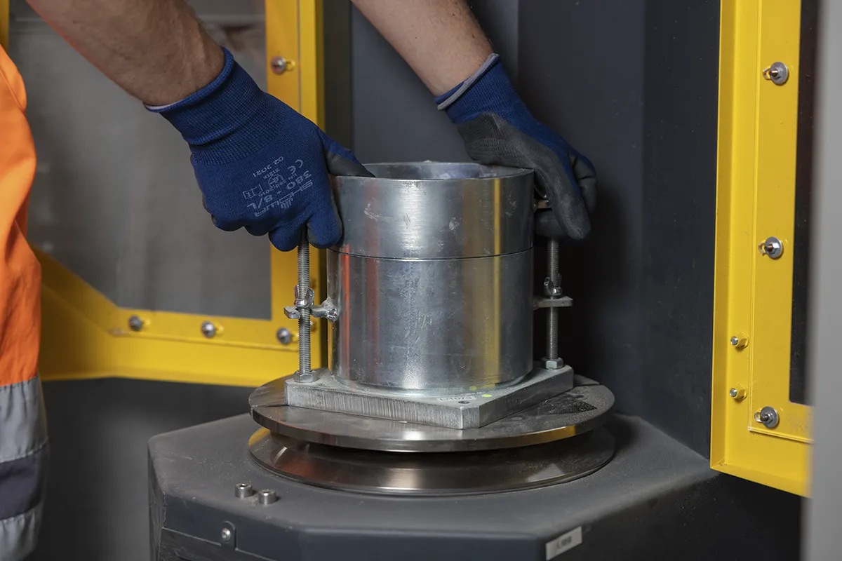 Tecnico Nuovolab posiziona campione cilindrico pressa laboratorio calcestruzzo
