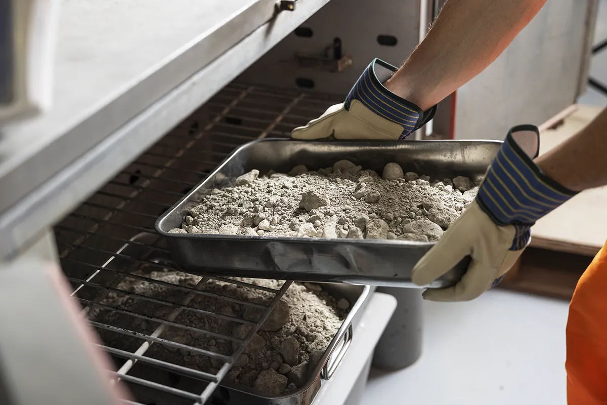 Tecnico Nuovolab infila vassoi campioni granulari forno essiccazione laboratorio