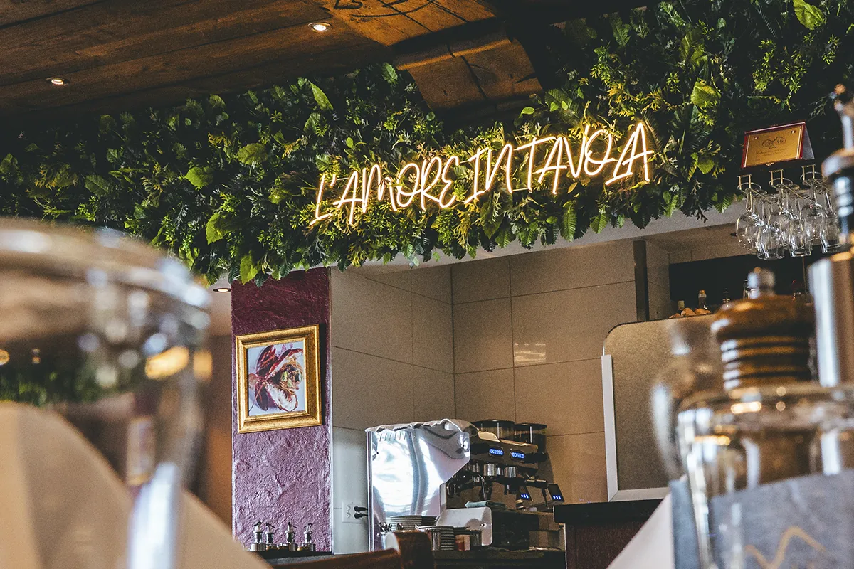 Scritta neon L'amore in tavola parete verde ristorante Core Mio Lugano